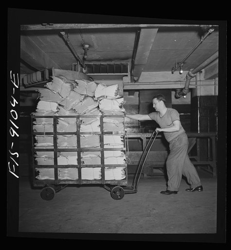 New York, New York. Mailroom of the New York Times newspaper. Bundles of papers are carried to trucks for distribution