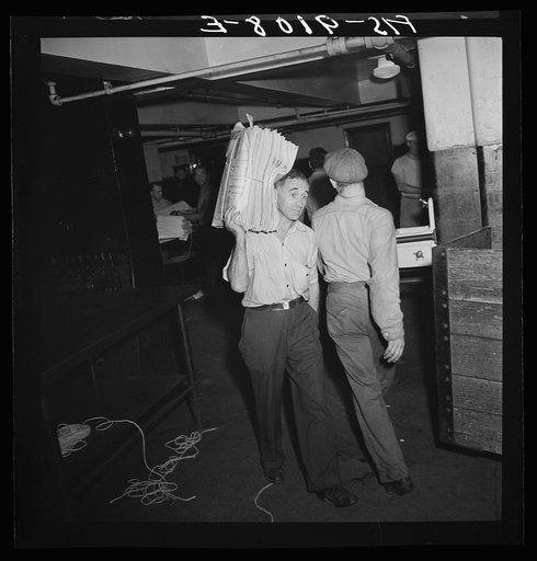 New York, New York. Mailroom of the New York Times newspaper. Bundles of papers are carried to trucks for distribution