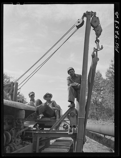 Little Rock, Arkansas to Missouri-Arkansas state line. War emergency pipeline from Longview, Texas to Norris City, Illinois. Pipeliners on one of the big caterpillar tractors used in raising and lowering pipe