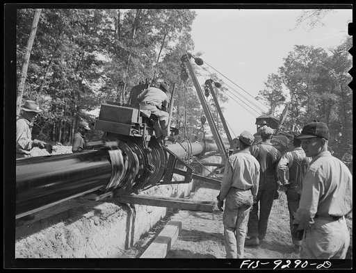 Untitled photo, possibly related to: Little Rock, Arkansas. To Missouri-Arkansas state line. War emergency pipeline from Longview, Texas to Norris City, Illinois. Priming pipe with hot asphalt paint. Crew follows machine and touches up by hand space where pipe is welded together