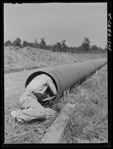 Arkansas-Texas state line to Gurdon, Arkansas. War emergency pipeline from Longview, Texas to Norris City, Illinois. Worker cleaning out any dirt that may be inside the pipe by sliding through sections of pipe before they are welded to main stem