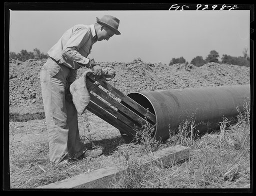 Arkansas-Texas state line to Gurdon, Arkansas. War emergency pipeline from Longview, Texas to Norris City, Illinois. Worker cleaning out any dirt that may be inside the pipe by sliding through sections of pipe before they are welded to main stem