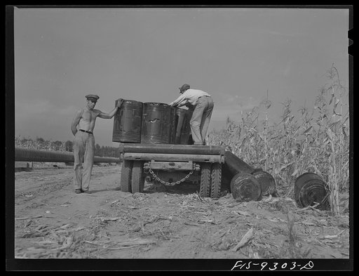 Untitled photo, possibly related to: Little Rock, Arkansas to Missouri-Arkansas state line. War emergency pipeline from Longview, Texas to Norris City, Illinois. Unloading barrels of primer along the line ahead of the priming crew. The pot firing crew will be along next to break this up and heat it