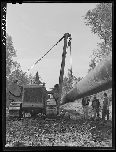 Untitled photo, possibly related to: Longview, Texas to Arkansas state line. War emergency pipeline from Longview, Texas to Norris City, Illinois. Preparing to hoist 200 foot section of welded pipe to position over ditch to join the main line