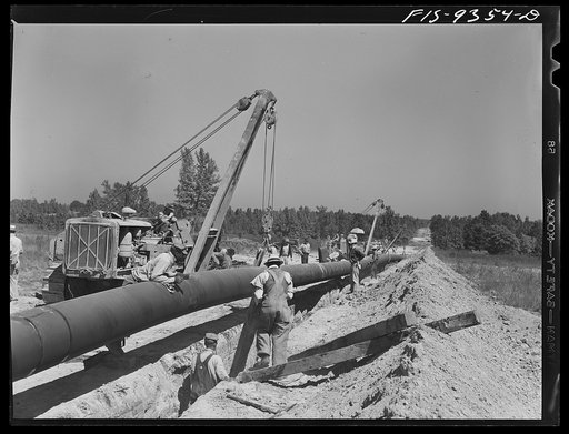 Untitled photo, possibly related to: Arkansas-Texas state line to Gurdon, Arkansas. War emergency pipeliine from Longview, Texas to Norris City, Illinois. Placing additional felt around piece of pipe which was found defectively wrapped by inspector