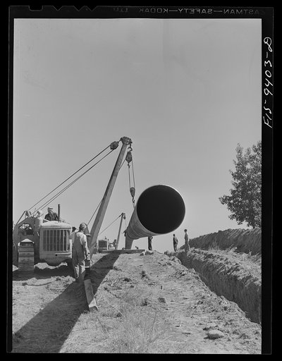 Untitled photo, possibly related to: Longview, Texas to Arkansas state line. War emergency pipeline from Longview, Texas to Norris City, Illinois. Preparing to hoist 200 foot section of welded pipe to position over ditch to join the main line