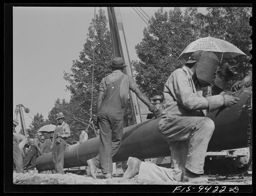 Little Rock, Arkansas to Missouri-Arkansas state line. War emergency pipeline from Longview, Texas to Norris City, Illinois. Stove pipe method of laying pipe. The man in the foreground is tack welding to main line section