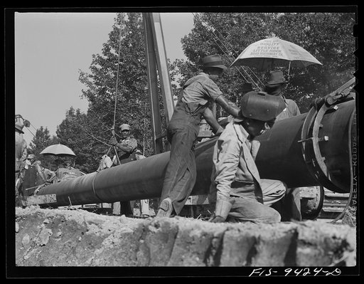 Untitled photo, possibly related to: Little Rock, Arkansas to Missouri-Arkansas state line. War emergency pipeline from Longview, Texas to Norris City, Illinois. Stove pipe method of laying pipe. The man in the foreground is tack welding to main line section