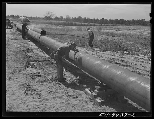 Longview, Texas to Arkansas state line. War emergency pipeline from Longview, Texas to Norris City, Illinois. Welders on the firing line. Assistant slowly rotates pipe while welders work