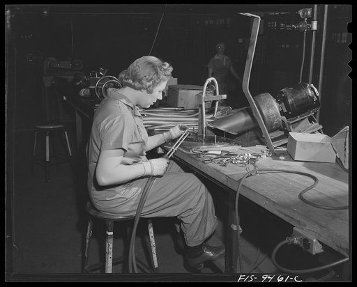De Soto bomber plant, Detroit, Michigan. Woman worker using brazing torch to solder bolts on end of pipe