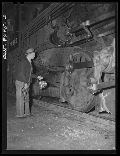 Tulsa, Oklahoma. Yard employee inspecting an engine which is passing through the yards at night