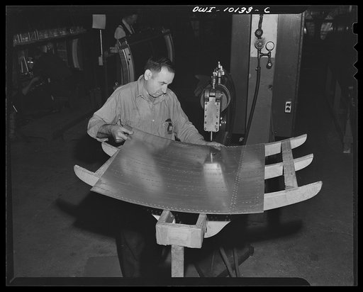 De Soto bomber plant. Detroit, Michigan. This operation is called "dimpling the skin". This is the outer covering of the center wing section, and the holes are made for the rivets to fit through
