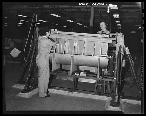 De Soto bomber plant, Detroit, Michigan. Women workers fitting the top skin to wing board flaps
