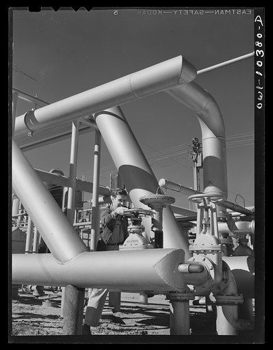 Worker operating the valve which controls incoming gas at a gasoline plant