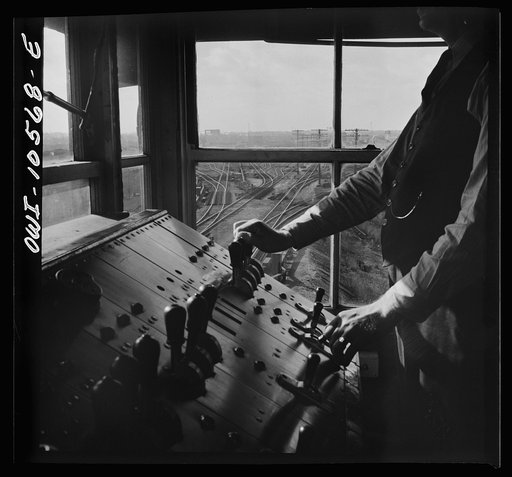 Untitled photo, possibly related to: Chicago, Illinois. A retarder operator at the south hump at an Illinois Central Railroad yard. From his control board he operates all the retarders and switches on his track