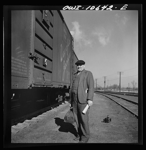 Chicago, Illinois. Conductor waiting to hop aboard the caboose of a southbound freight at an Illinois Central Railroad yard
