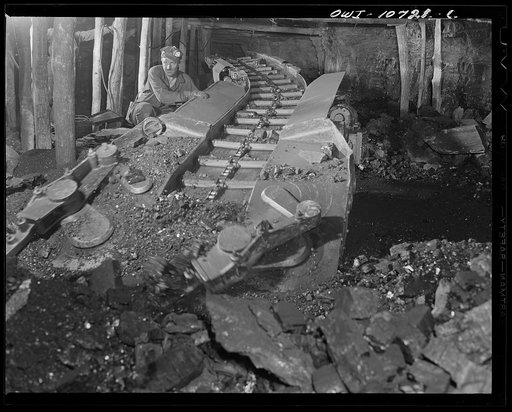 Pittsburgh, Pennsylvania (vicinity). Montour no. 4 mine of the Pittsburgh Coal Company. After coal has been shot down by blasting, a mechanical loader is rolled into the "room". Electrically driven steel arms gather the coal and a conveyor belt moves it out to a waiting car