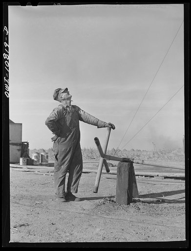 Moore County, Texas. Tool dresser (cable tool driller's helper) operating valve which shuts off gas pressure during drilling operations