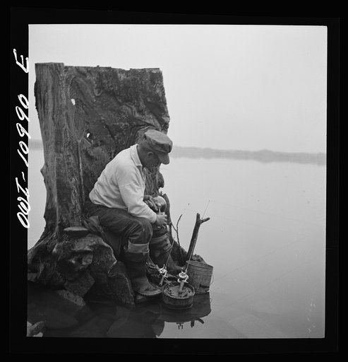 Lancaster County, Pennsylvania. Fishing for salmon on the Susquehanna River at 6 p.m. This man is a state supervisor of highways. In his time off late in the afternoon he fishes with a bottle of hard cider beside him