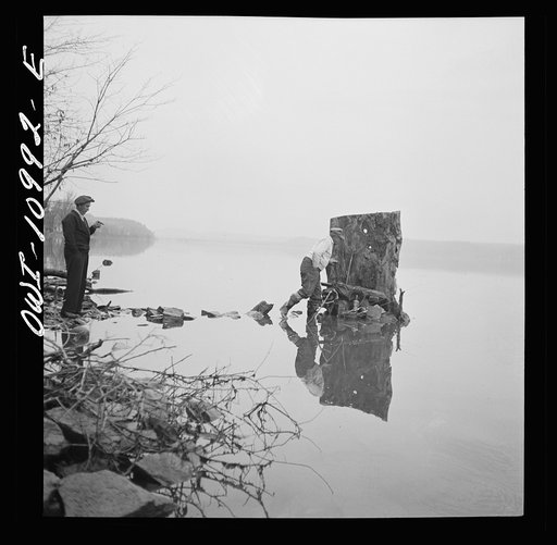 Untitled photo, possibly related to: Lancaster County, Pennsylvania. Fishing for salmon on the Susquehanna River at 6 p.m. This man is a state supervisor of highways. In his time off late in the afternoon he fishes with a bottle of hard cider beside him