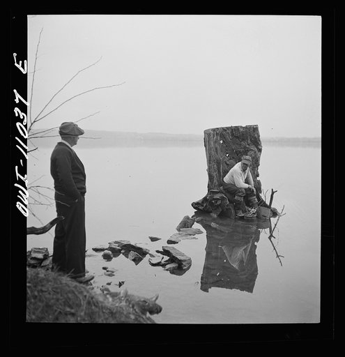 Lancaster County, Pennsylvania. Fishing for salmon on the Susquehanna River at 6 p.m. This man is a state supervisor of highways. In his time off late in the afternoon he fishes with a bottle of hard cider beside him