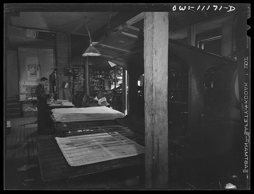 Untitled photo, possibly related to: Lititz, Pennsylvania. Cutting and folding machine in the Lititz Record-express office. Owner and publisher William N. Young (foreground), who is short of help, feeds the papers himself