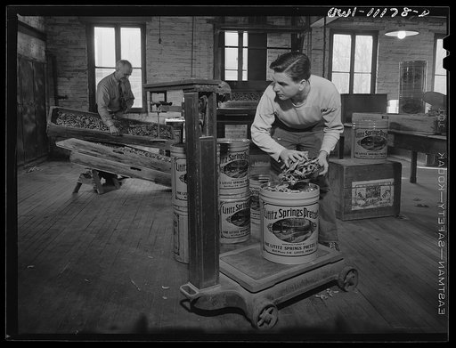 Lititz, Pennsylvania. Lititz Springs Pretzel Company, owned by Lewis C. Haines (background) who is unloading a tray of pretzels which has come up on a dumb waiter from the baking room below. A son, Bob, weighs them and packs them in cans. Lititz was the first town in America where pretzels were made