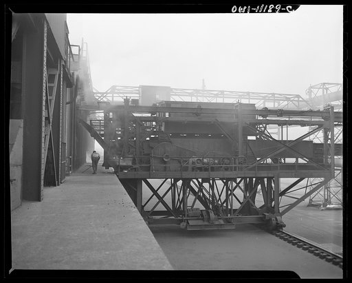 Hanna furnaces of the Great Lakes Steel Corporation. Detroit, Michigan. Coke oven pusher. A long square pusher is inserted through the entire section of the coke oven, thus pushing the coke out to the other side into the freight car. This coke oven is a modern by-product oven. All the gases and vapo