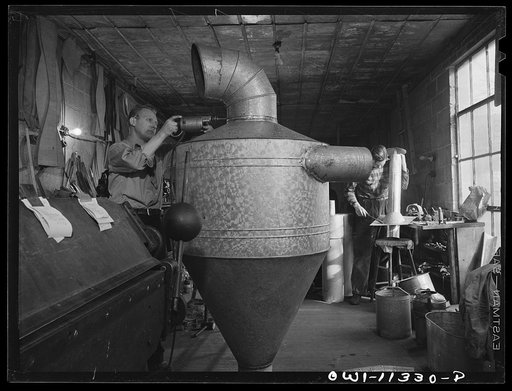 Untitled photo, possibly related to: Lititz, Pennsylvania. Machine shop back of Morris Kreider's hardware store where he makes small parts for neighboring defense plants. Here he is working on a "cyclone" or dust collector for the Hackman Furniture Company, now making propellors. Kreider expects his