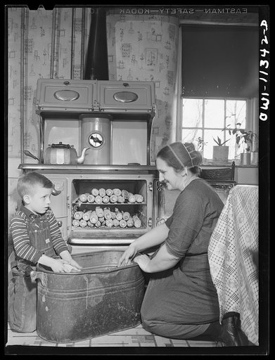 Lititz, Pennsylvania. Mennonite farmer's wife and her son husking corn which has been dried out in the oven. It will then be taken to a mill to be ground for cornmeal