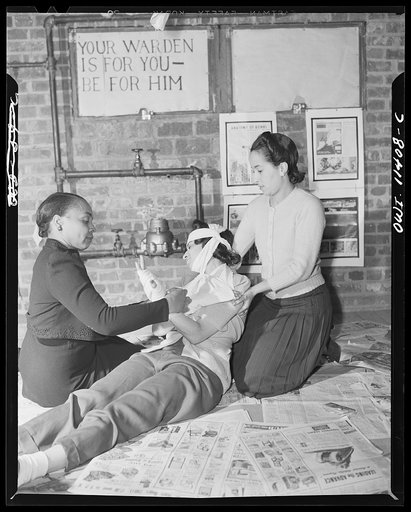 Washington, D.C. First aid class of the air raid warden unit in the Southwest area. Two future first-aiders practicing on a member of the class. The instructor gives problems and the students must carry them out as they would in an actual bombing