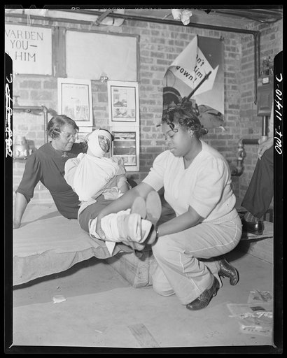 Washington, D.C. First aid class of the air raid warden unit in the Southwest area. Two members of the class applying splints and other bandages to a practice victim