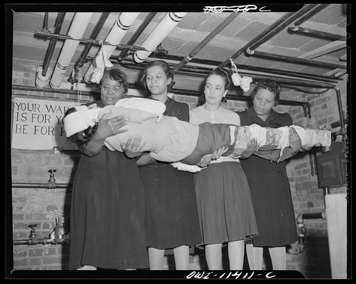 Washington, D.C. First aid class of the air raid warden unit in the Southwest area. Four members of the class demonstrating the proper way to transport a victim if a stretcher is not available