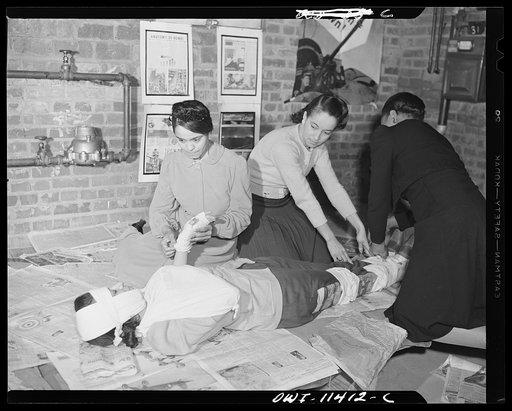 Washington, D.C. First aid class of the air raid warden unit in the Southwest area. Three members of the class applying splints, hand, head and arm bandages to a member of the class