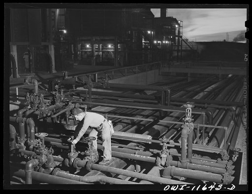 Borger, Texas. Worker on night tour operating valve in Phillips refinery