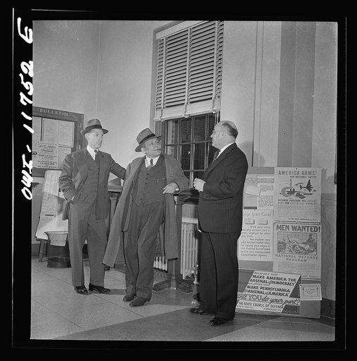 Lititz, Pennsylvania. Postmaster Robert Pautz chatting with two friends in the post office. He has three sons and one son-in-law in the service, and his daughter works in the U.S. War Department, so he has every reason to push the sale of war bonds. He plasters his post office with every available p
