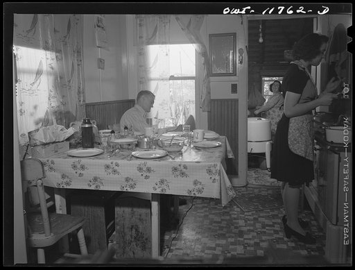 Lititz, Pennsylvania. Mrs. R.W. (Elizabeth) Almoney, forty-seven (center rear), has had eleven children. She works as a gauge inspector at the Animal Trap Company and on Sunday does the washing. Her husband (left) works in the local chocolate factory. Daughter Arline, twenty (right), who also works 