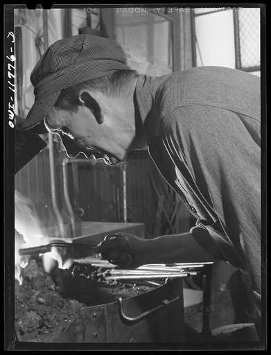 Lititz, Pennsylvania. Ellis Spickler has been working at the Animal Trap Company since 1909; he finds a blacksmith's forge the best way to harden and temper setting tools