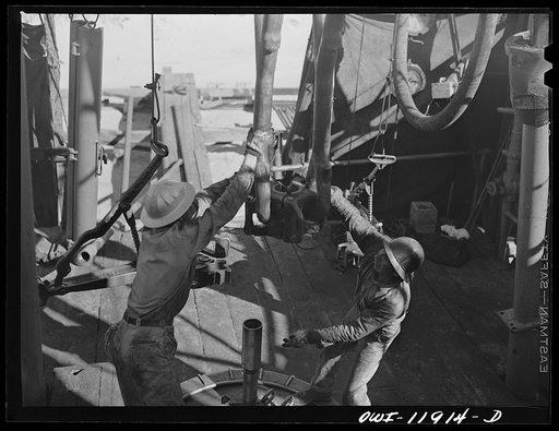 Andrews County, Texas. Reaching for descending traveling block while pulling the drill pipe out of a well to change the bit