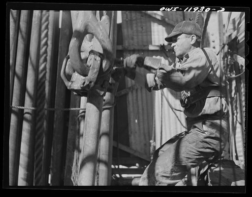 Untitled photo, possibly related to: Andrews County, Texas. Derrick man moving pipe into position as it is brought up out of the hole for changing the bit
