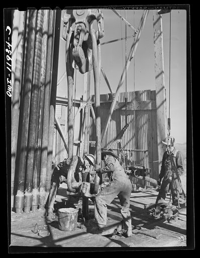 Andrews County, Texas. Clamping a traveling block to piece of drill pipe to be hoisted out of hole