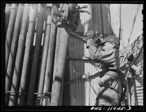 Untitled photo, possibly related to: Andrews County, Texas. Derrick man putting pulled drill pipe in place. He is 120 feet above the ground
