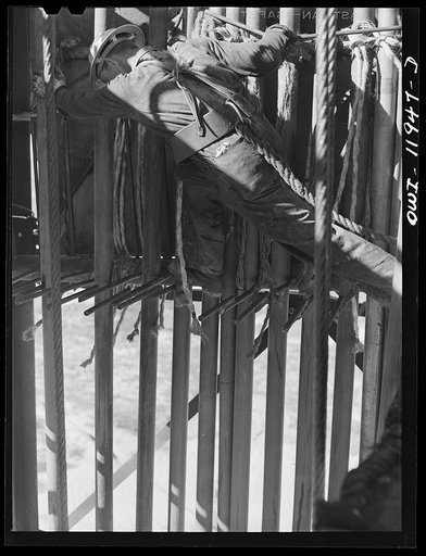 Andrews County, Texas. Derrick man putting pulled drill pipe in place. He is 120 feet above the ground