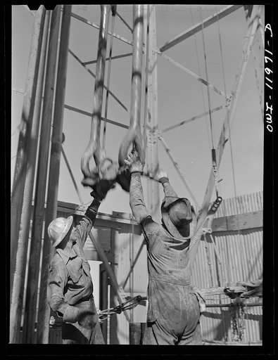 Untitled photo, possibly related to: Amdrews County, Texas. Roughnecks reaching for descending traveling block during pipe pulling operations