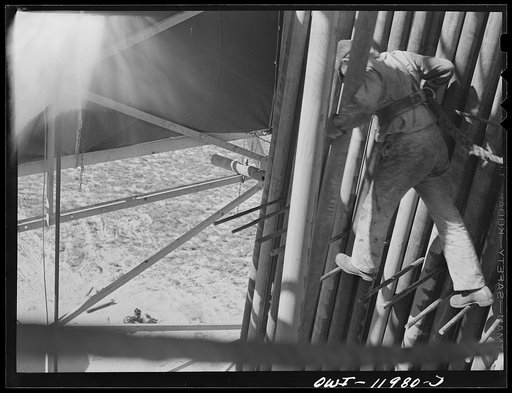 Untitled photo, possibly related to: Andrews County, Texas. Derrick man putting pulled drill pipe in place. He is 120 feet above the ground