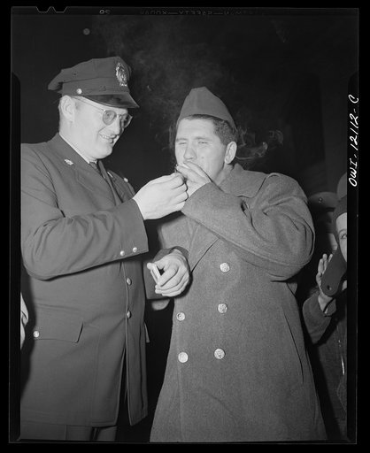 Washington, D.C. Union Station policeman lighting the cigarette of a soldier waiting to catch a troop train
