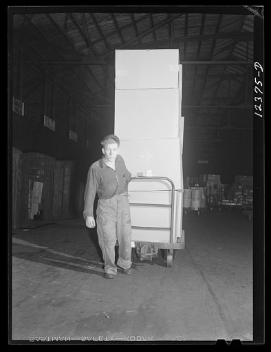 Chicago, Illinois. Workman hauling a hand truck loaded with goods at a freight house at a Chicago and Northwestern Railroad yard. The men are paid according to the tonnage handled per day