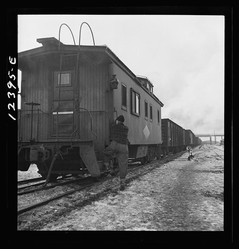 Chicago, Illinois. Freight conductor boarding the caboose of a train bound for the west coast out of Chicago and Northwestern Railroad yard