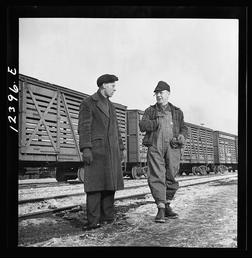 Chicago, Illinois. Freight conductor (right) talking to a yardmaster as he waits for the caboose of his train to come by at a Chicago and Northwestern Railroad yard