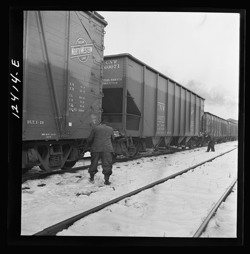 Chicago, Illinois. Workmen inspecting journal boxes of a train in a Chicago and Northwestern Railroad departure yard